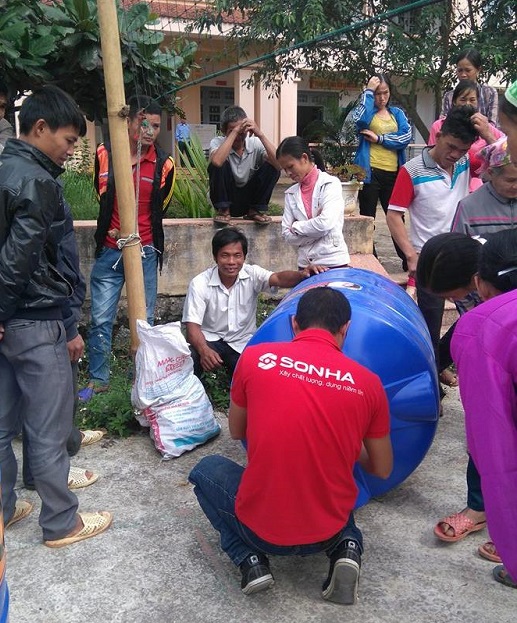 Các thành viên công ty Sơn Hà hỗ trợ giao bồn nhựa cho các hộ gia đình